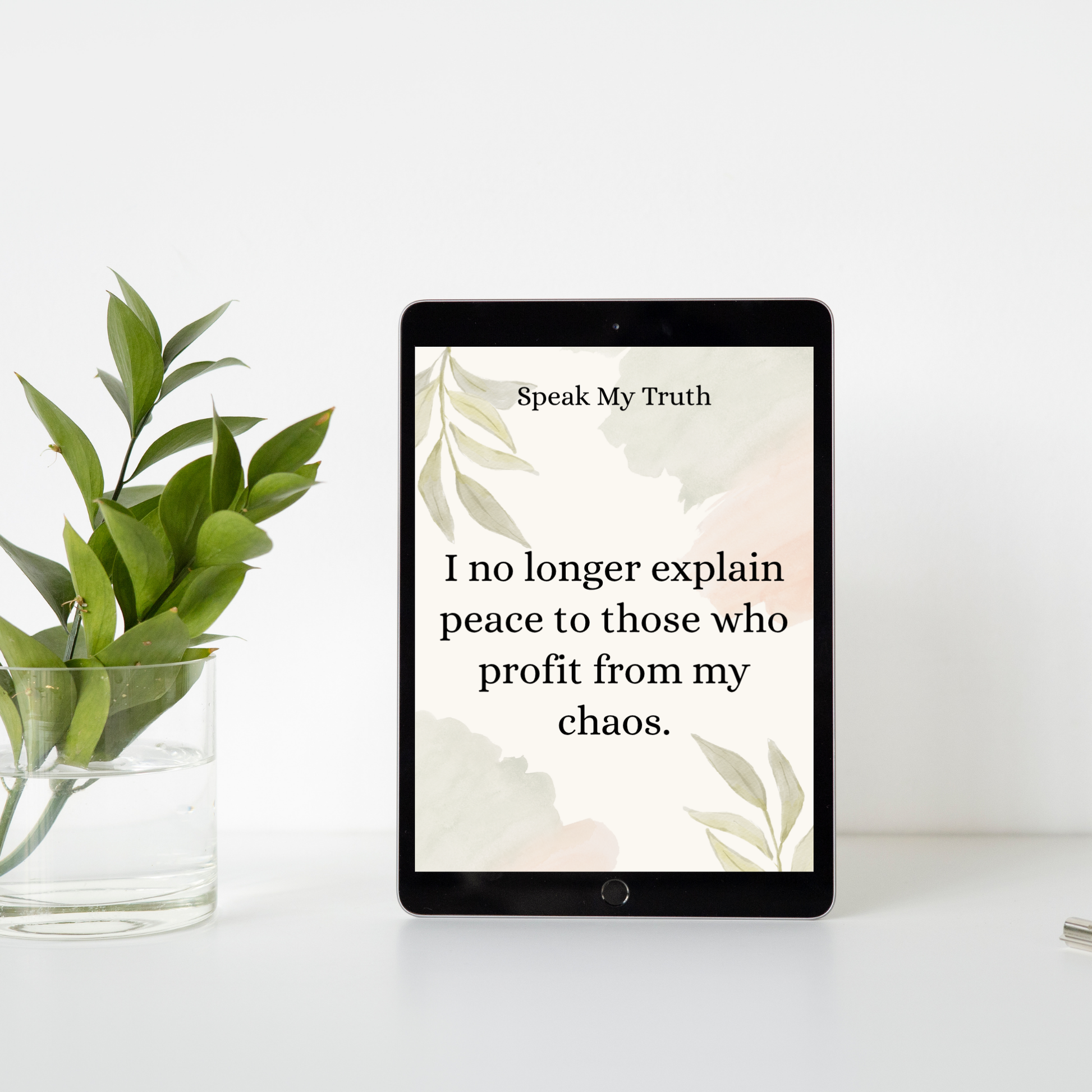 Digital affirmation card displayed on a tablet beside a clear vase with green leaves against a white wall.